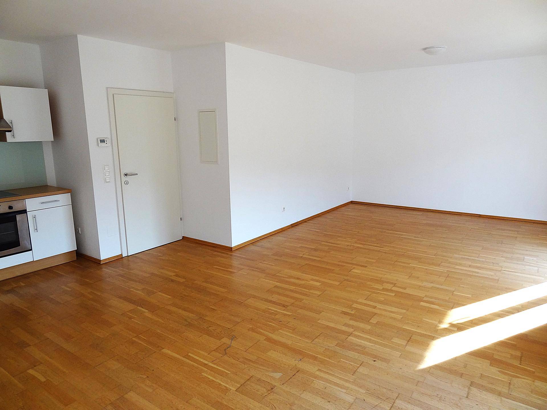 Lichtdurchfluteter Wohnraum mit warmem Parkettboden und neutralen Wänden, bereit für persönliche Gestaltung.