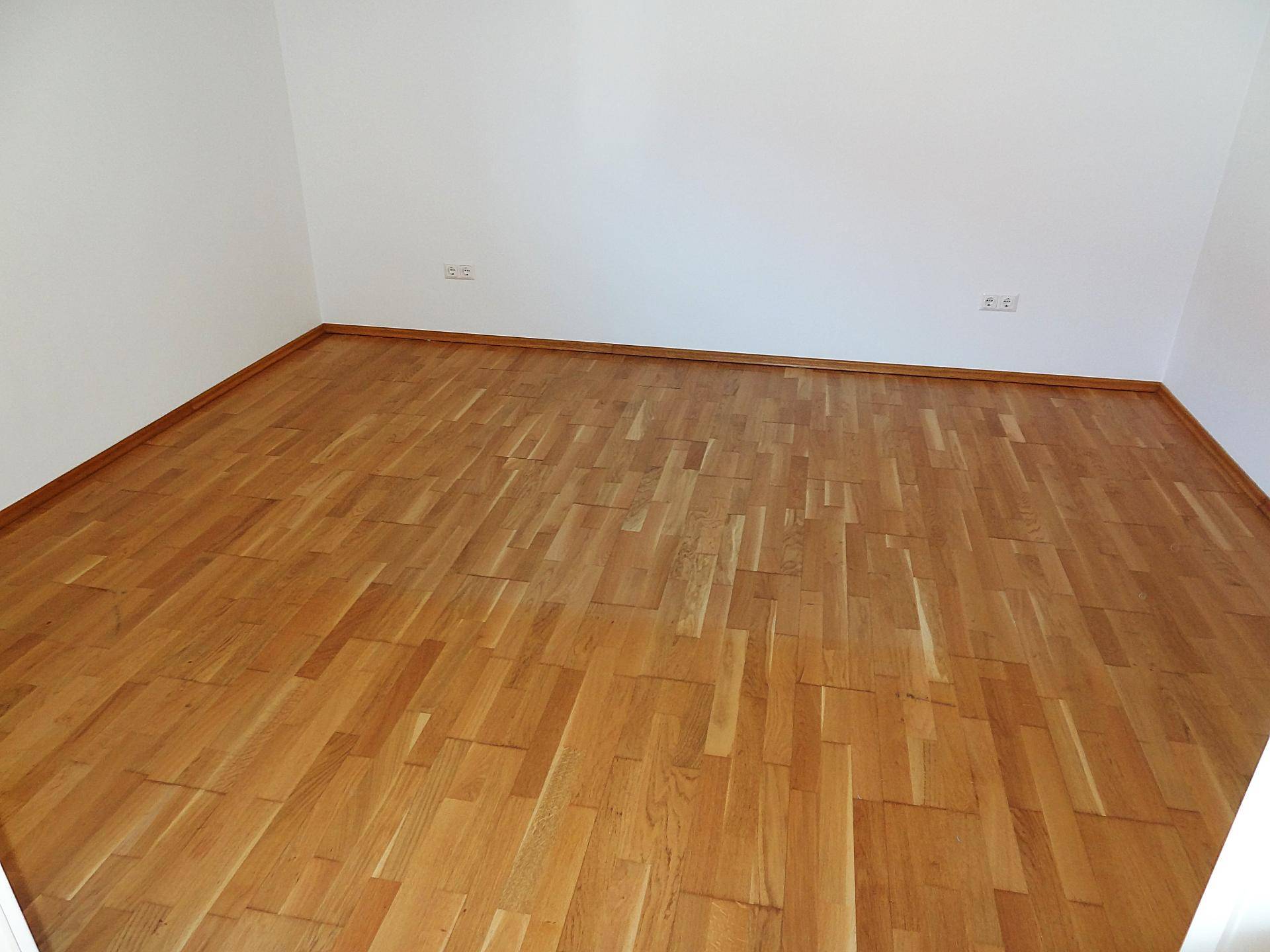 Leerer Raum mit warmem Parkettboden und sauberen weißen Wänden, ideal für neue Mieter.
