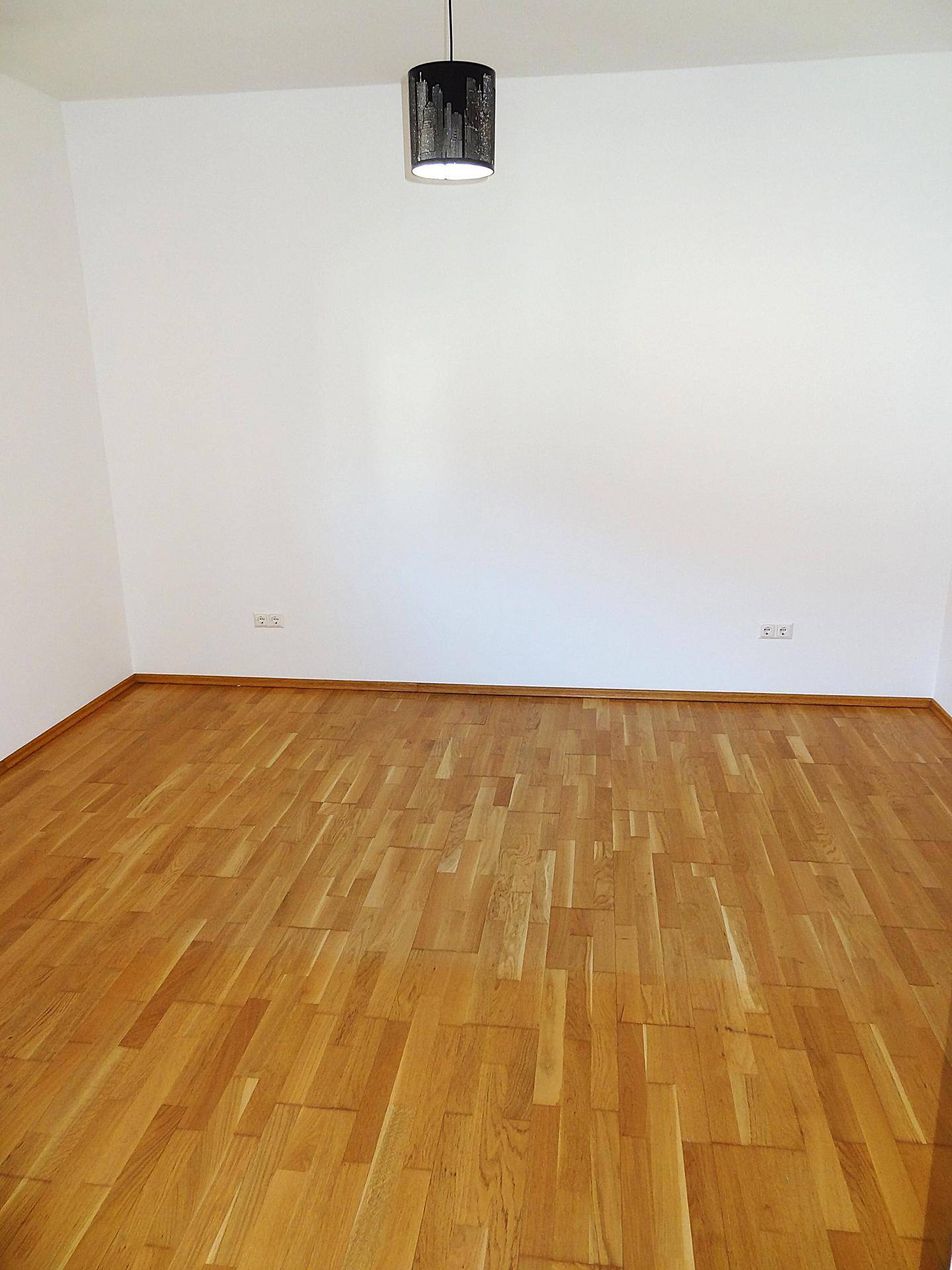 Heller Raum mit Parkettboden und einer modernen Deckenleuchte, bereit zum Einzug.
