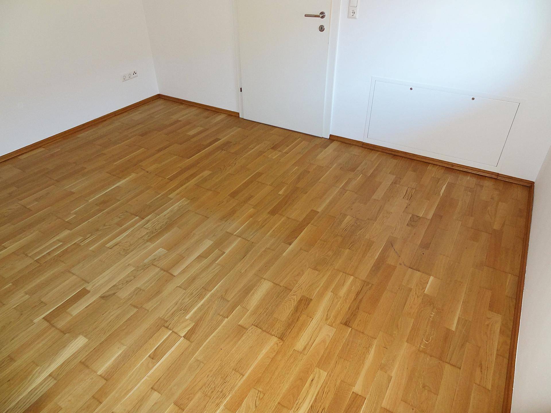 Sauberer, leerer Raum mit hellem Parkettboden und weißen Wänden, ideal für vielfältige Nutzung.