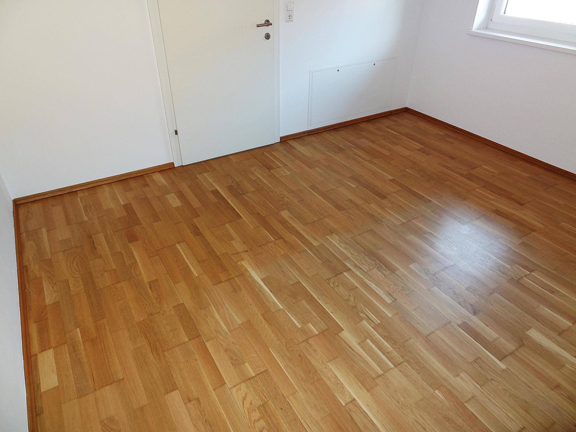 Leerer Raum mit gepflegtem Parkettboden und weißen Wänden, bereit für individuelle Einrichtung.