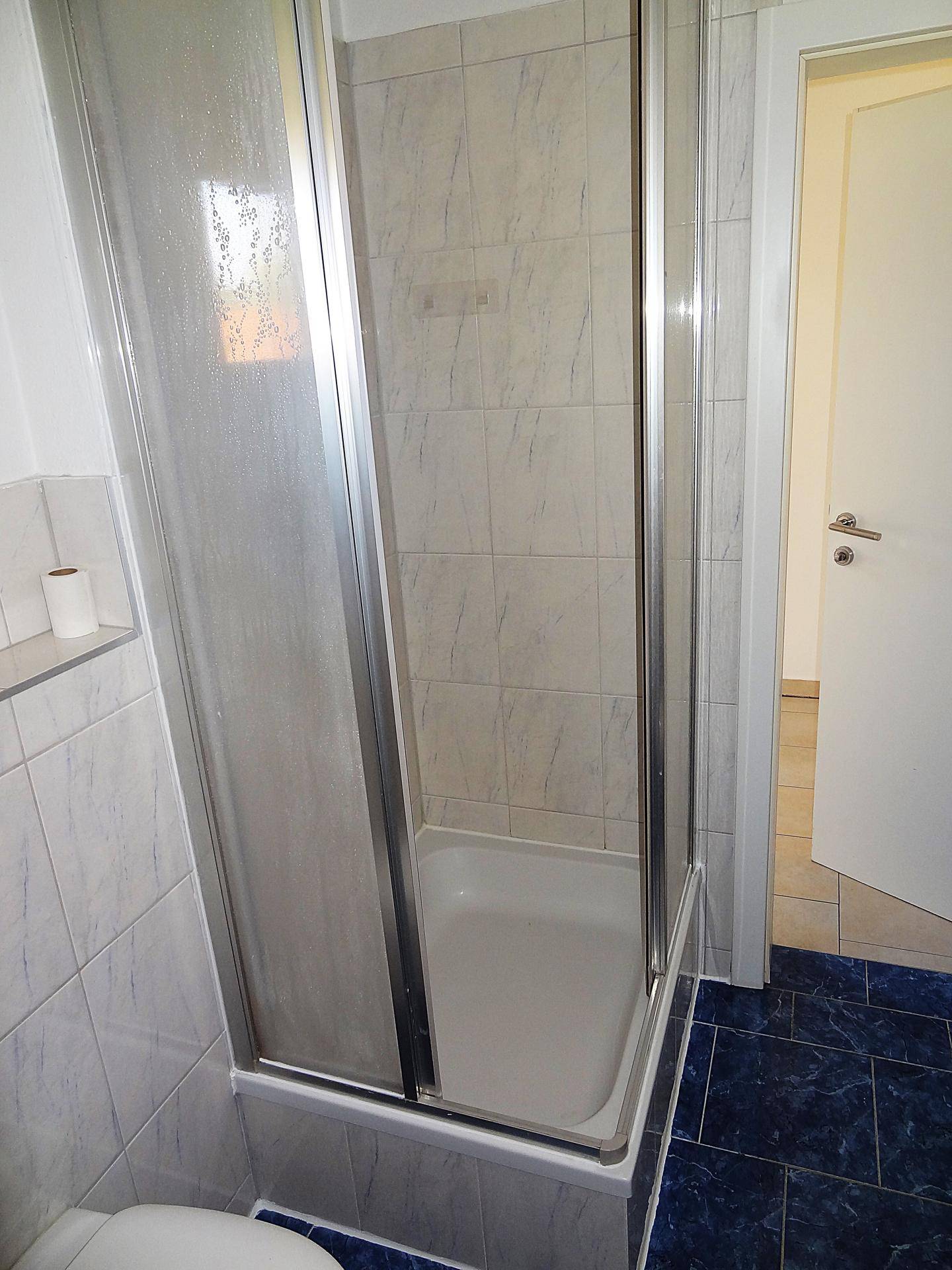 Duschkabine mit Glaswänden und Duschwanne im Badezimmer, sauber und funktional.