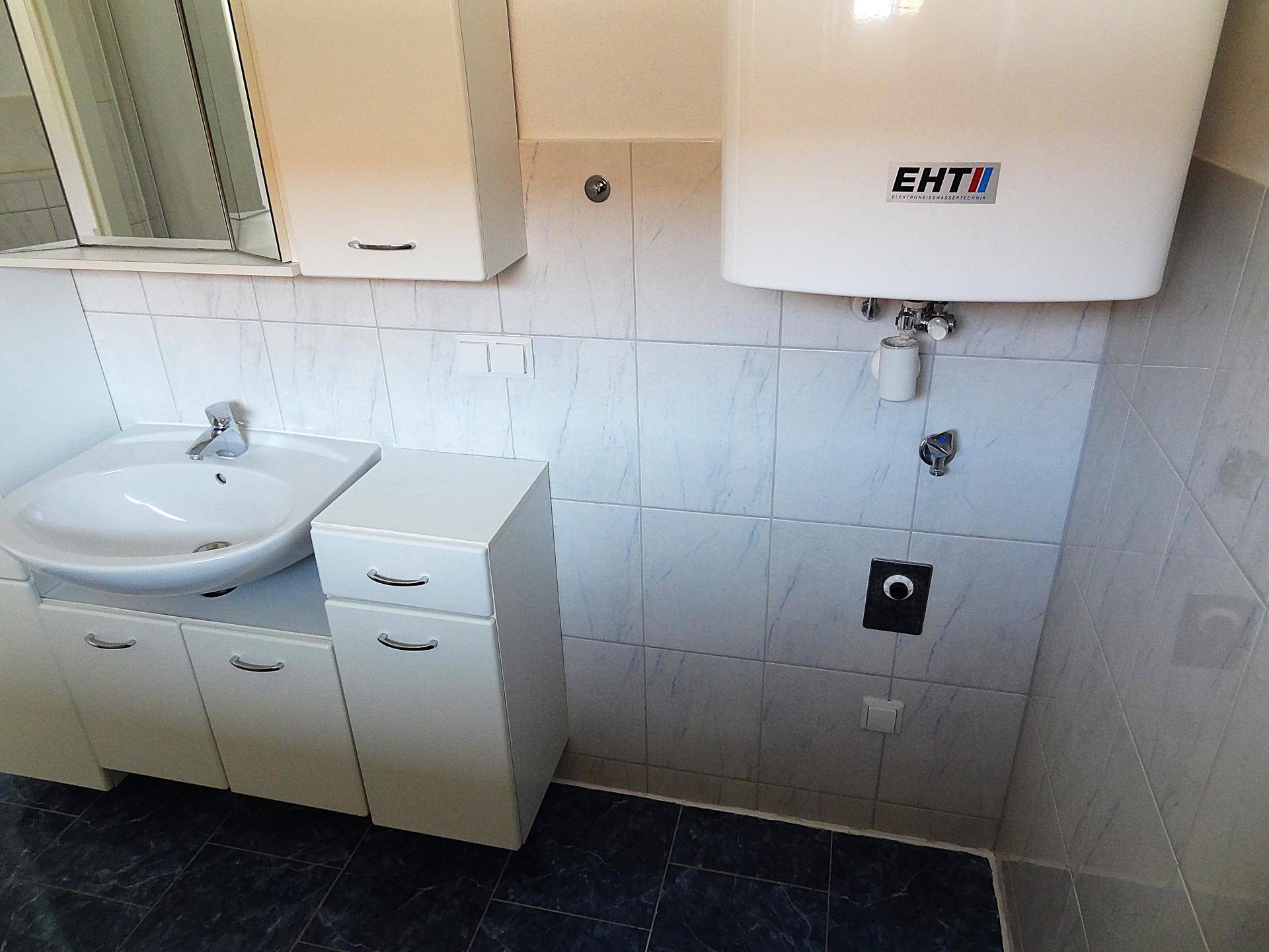 Badezimmer mit Waschtisch, Spiegelschrank und Boiler, bietet praktischen Stauraum.