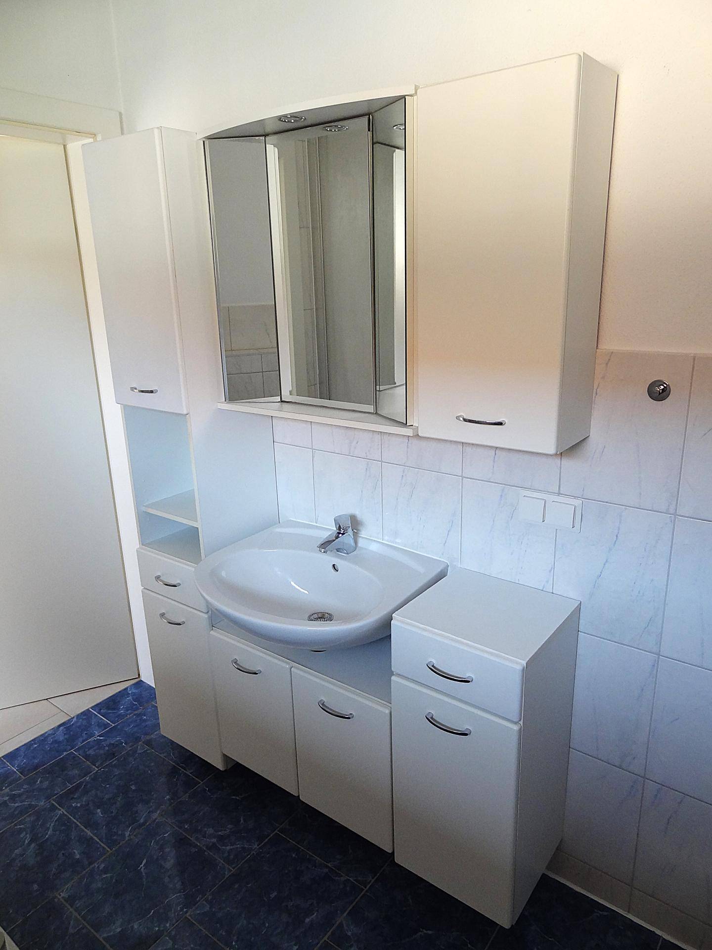 Waschtisch mit integriertem Waschbecken, Spiegelschrank und zusätzlichen Badmöbeln.