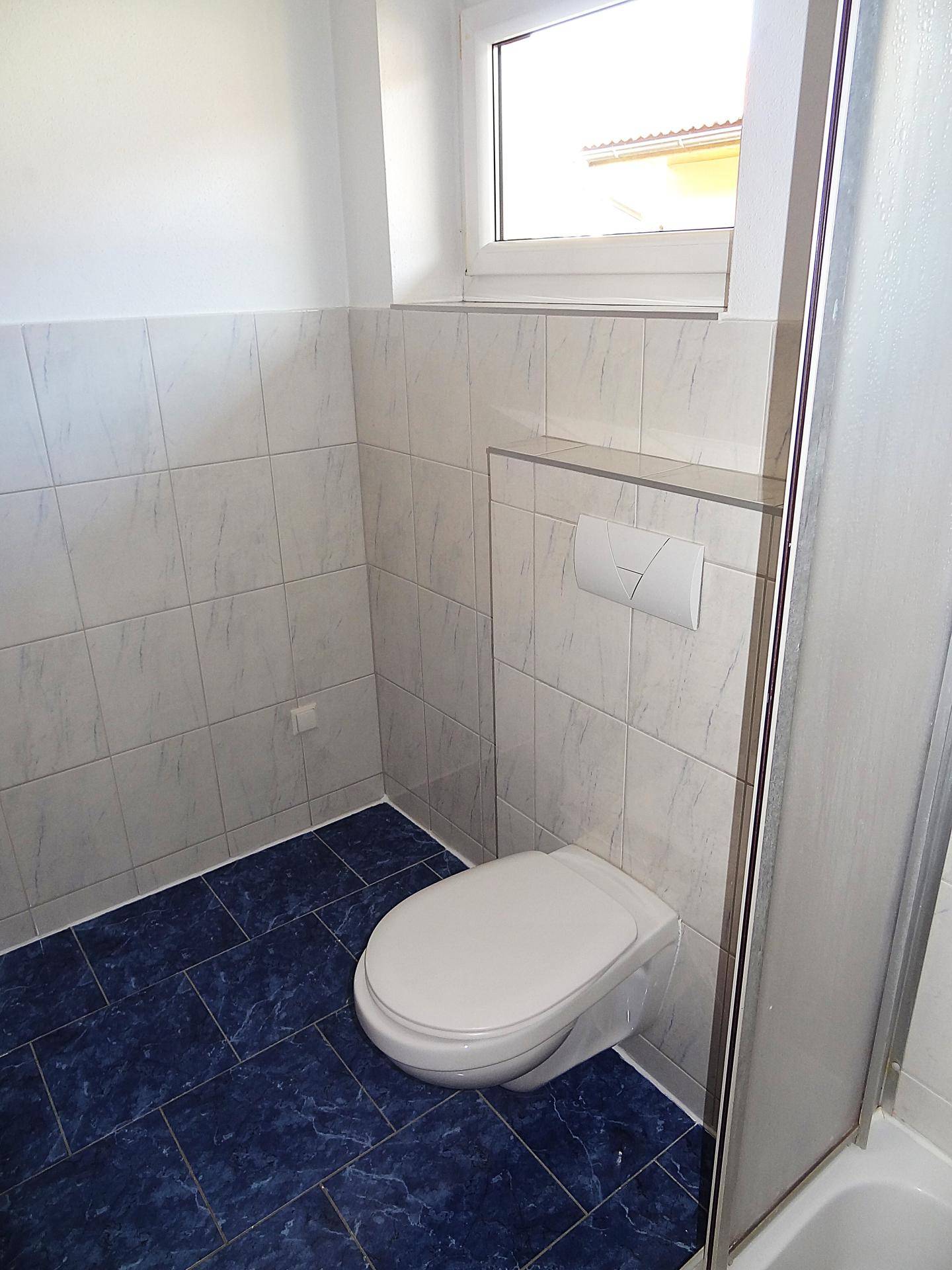 Wandhängendes WC und Fenster im Badezimmer, sorgt für gute Belüftung und Helligkeit.