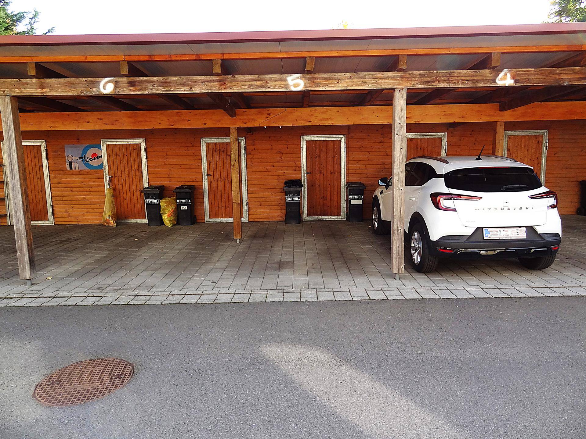 Detailansicht des Carports mit nummerierten Stellplätzen und individuellen Holzabstellräumen.