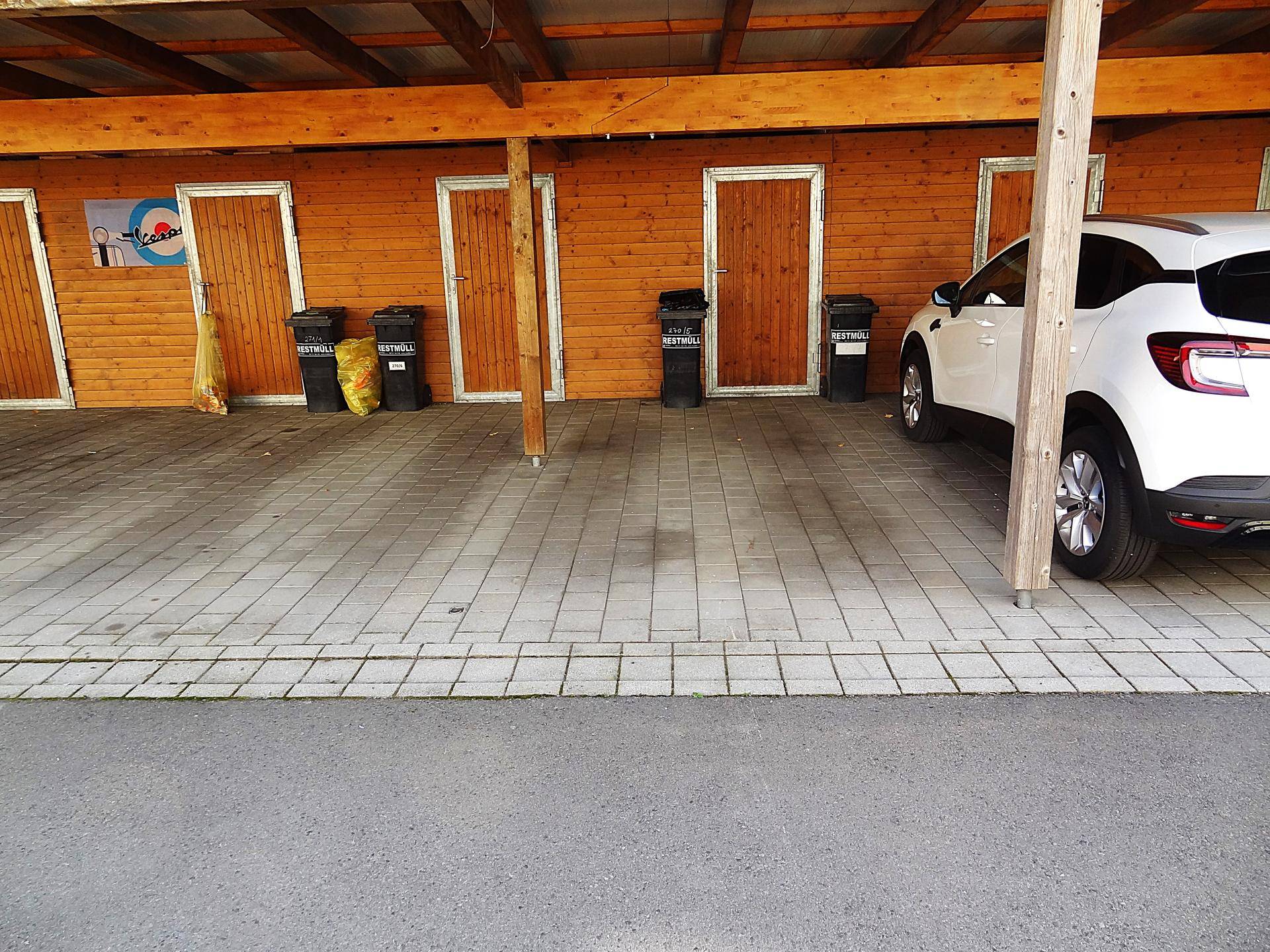 Carport-Bereich mit Holzverkleidung und praktischen Abstellräumen, ideal für zusätzlichen Stauraum.