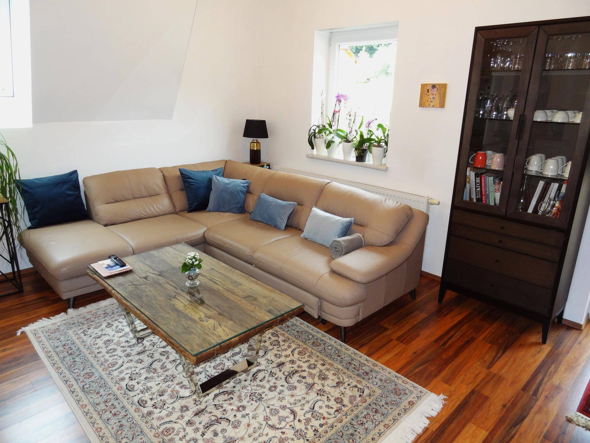 Gemütlicher Wohnbereich mit Ledersofa, Couchtisch und Teppich auf Holzboden.