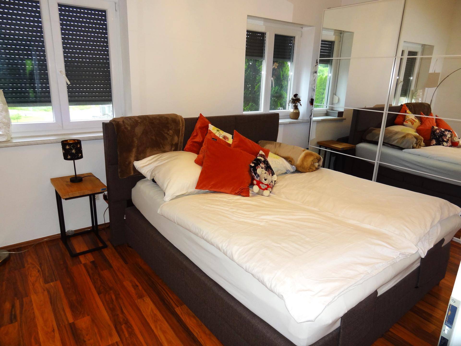 Gemütliches Schlafzimmer mit Doppelbett, Holzboden und Spiegelschrank.