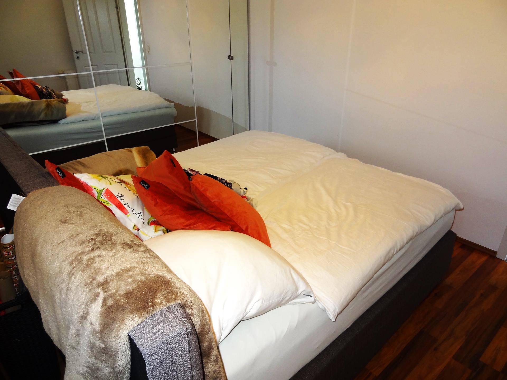 Gemütliches Schlafzimmer mit Doppelbett, Holzboden und Spiegelschrank.