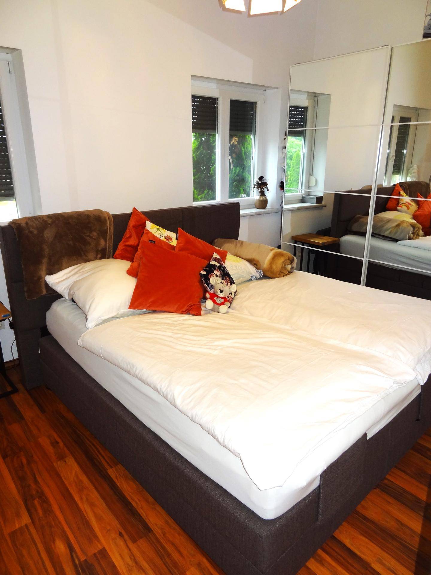 Helles Schlafzimmer mit großem Bett, Holzfußboden und Spiegelschrank, der den Raum optisch vergrößert.