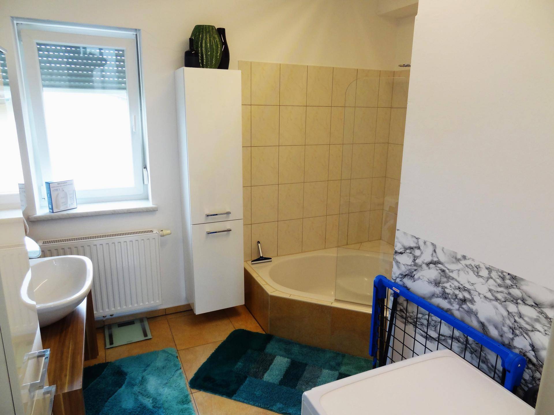 Praktisches Badezimmer mit beigefarbenen Fliesen, Eckbadewanne und Duschabtrennung aus Glas.