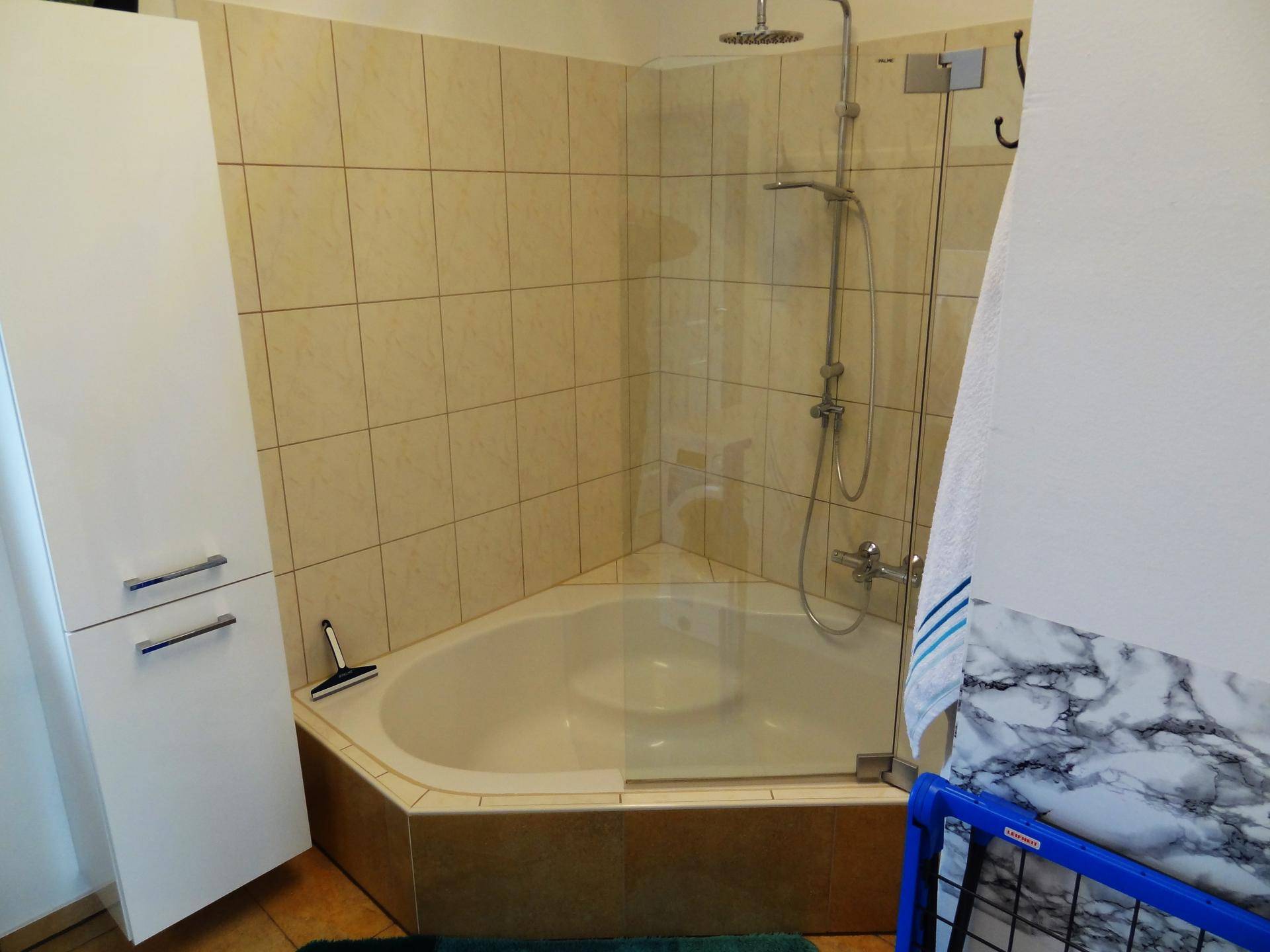 Eckbadewanne mit integrierter Duschfunktion und Glasabtrennung im Badezimmer, ideal für kleine Räume.