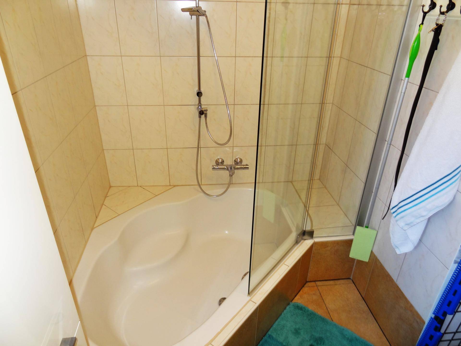 Eckbadewanne mit Duschfunktion und beigefarbenen Fliesen im Badezimmer, die eine zeitlose Optik bieten.