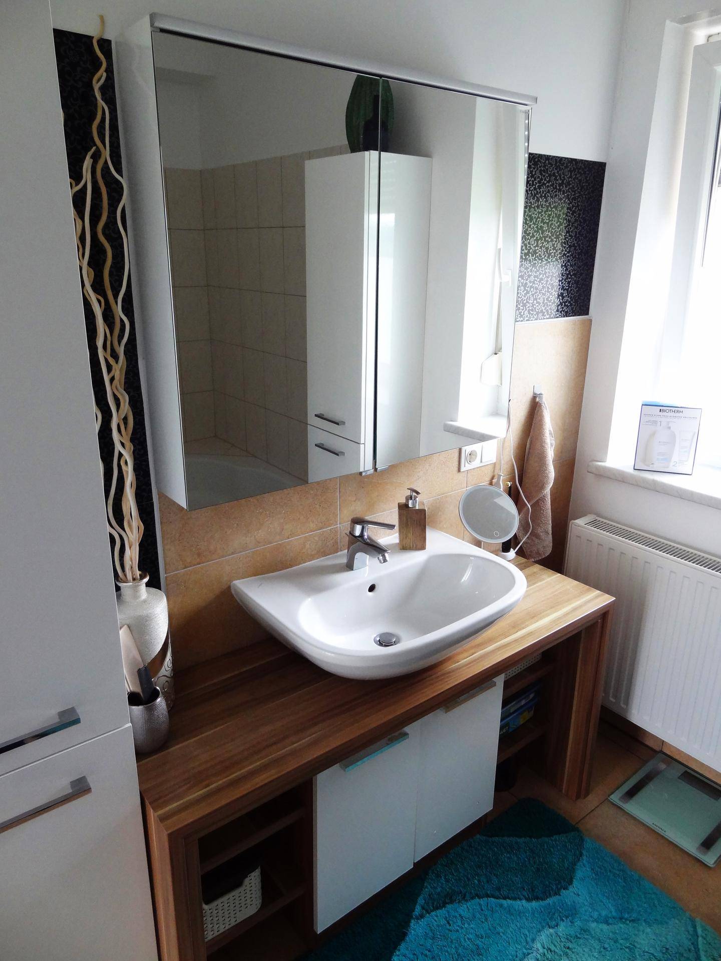 Badezimmer mit großem Spiegelschrank über dem Waschbecken und einem Fenster, das viel Licht hereinlässt.