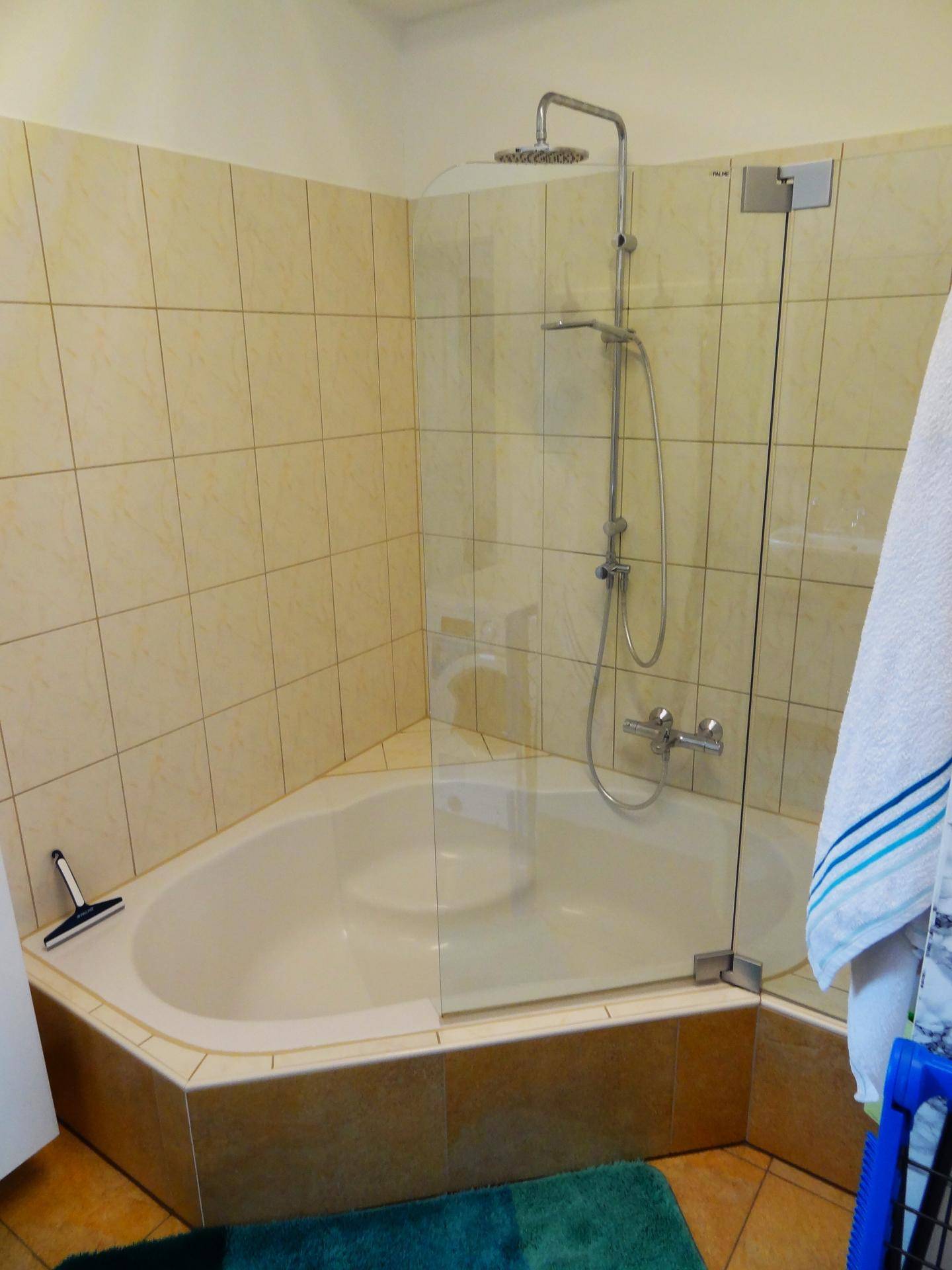 Dusch-Badewannen-Kombination mit Regendusche und beigefarbenen Wandfliesen, die eine warme Atmosphäre schaffen.