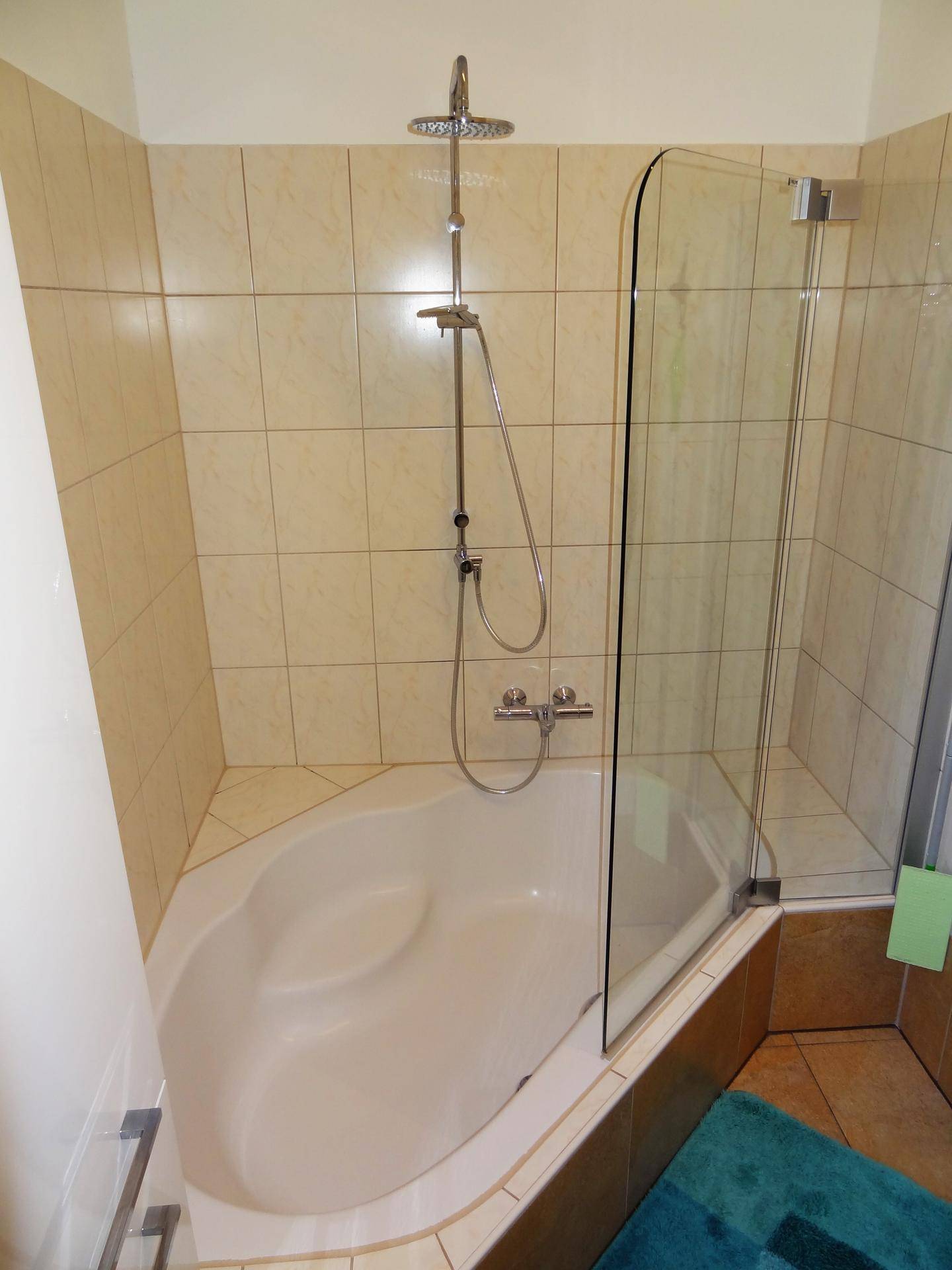 Dusch-Badewannen-Kombination mit Regendusche und beigefarbenen Wandfliesen, die den Raum hell wirken lassen.