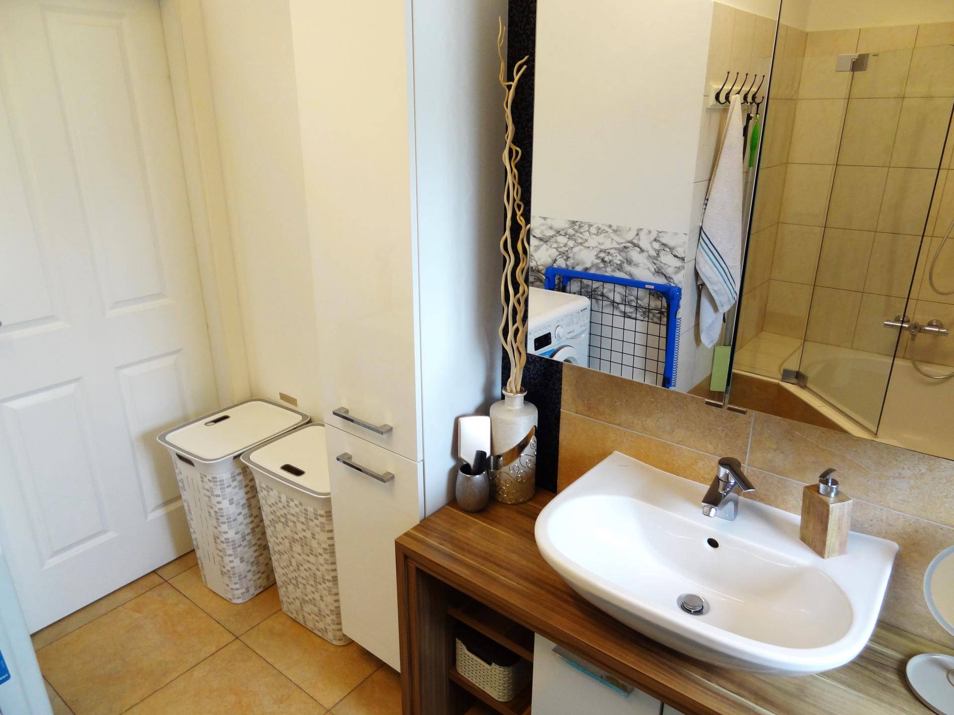 Badezimmer mit Waschbecken, Spiegelschrank und integrierter Waschmaschine für zusätzlichen Komfort.