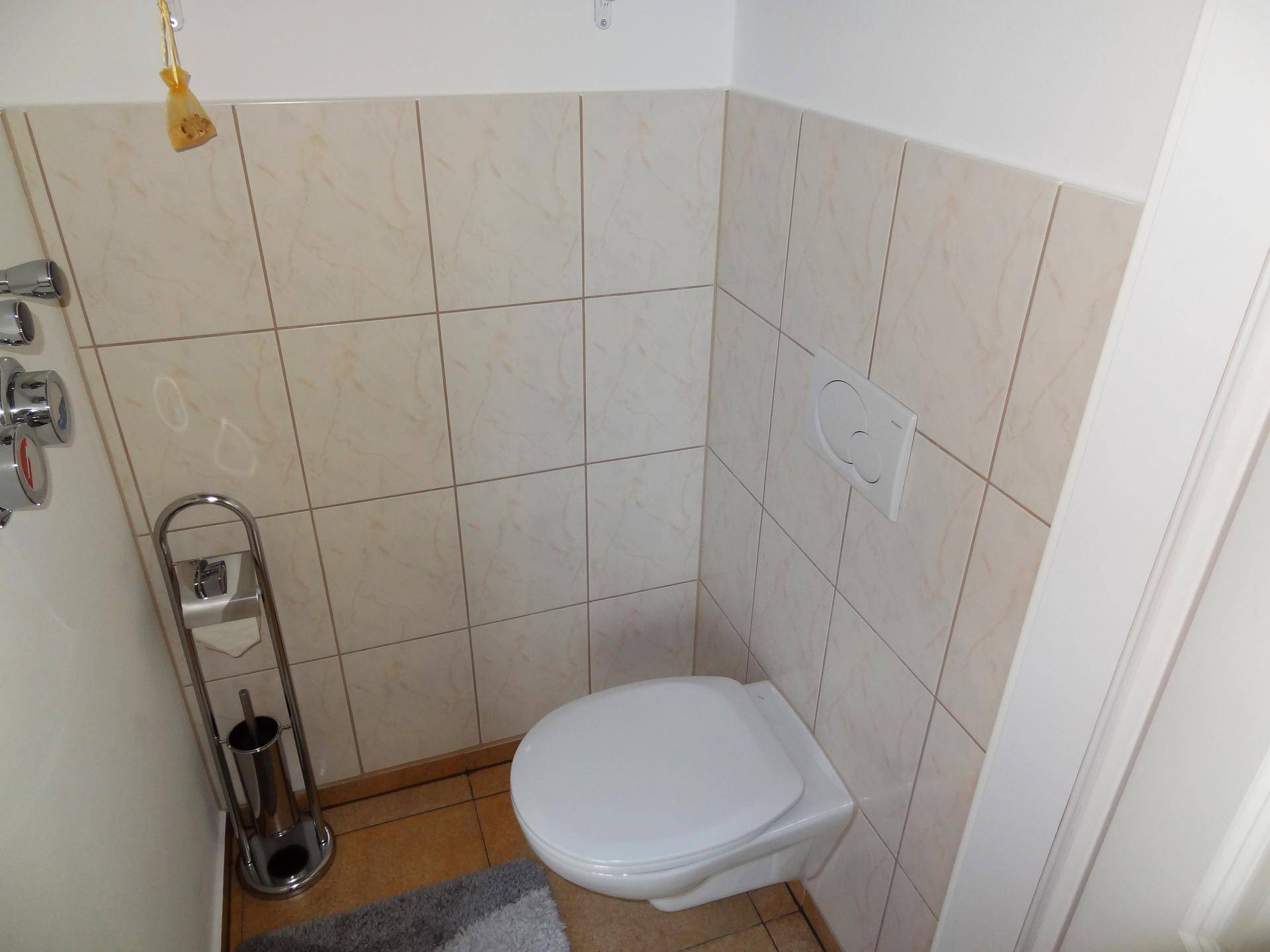 Kleines Gäste-WC mit heller Fliesenverkleidung und wandhängendem WC für einfache Reinigung.