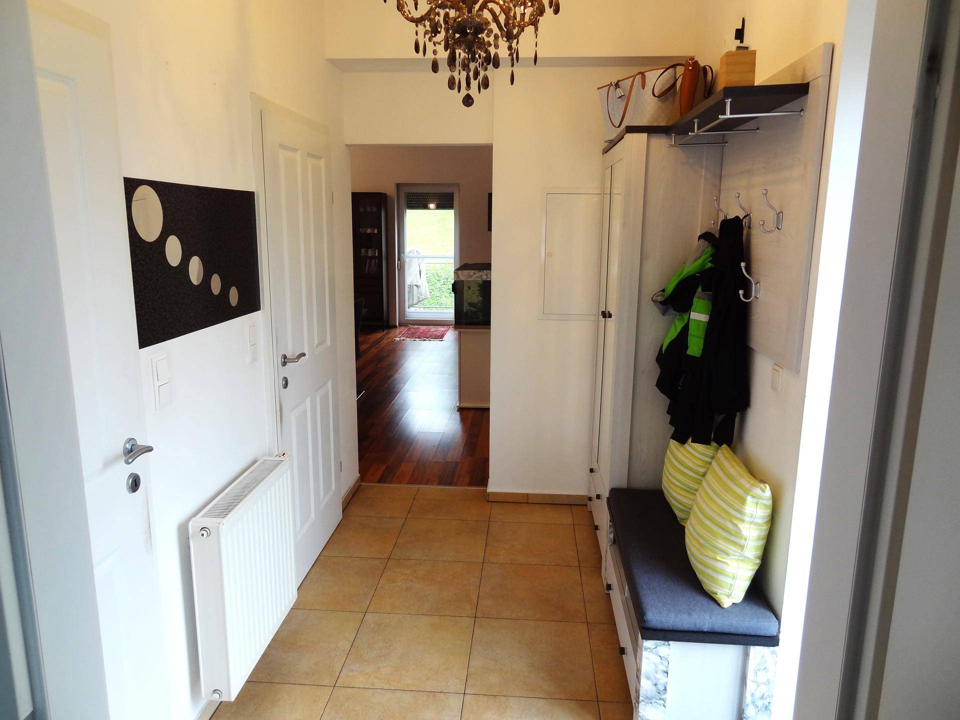 Eingangsbereich mit Garderobe, Fliesenboden und Übergang zum Wohnbereich mit Parkett.
