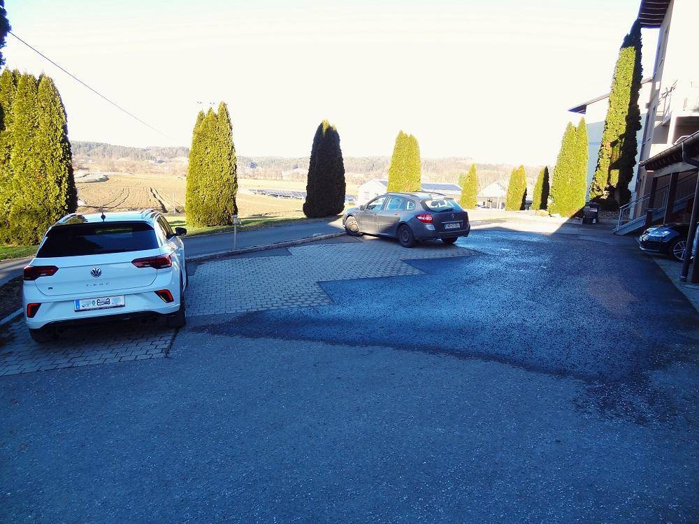 Außenparkplätze auf gepflastertem Bereich mit Blick auf die umliegende Landschaft und Felder.