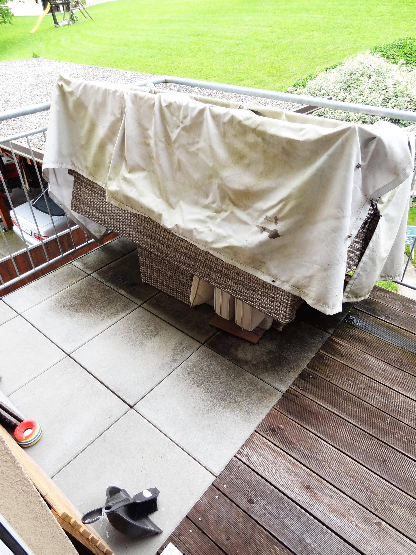 Balkon mit Holzboden und Fliesen, teilweise überdachten Gartenmöbeln und Blick ins Grüne.