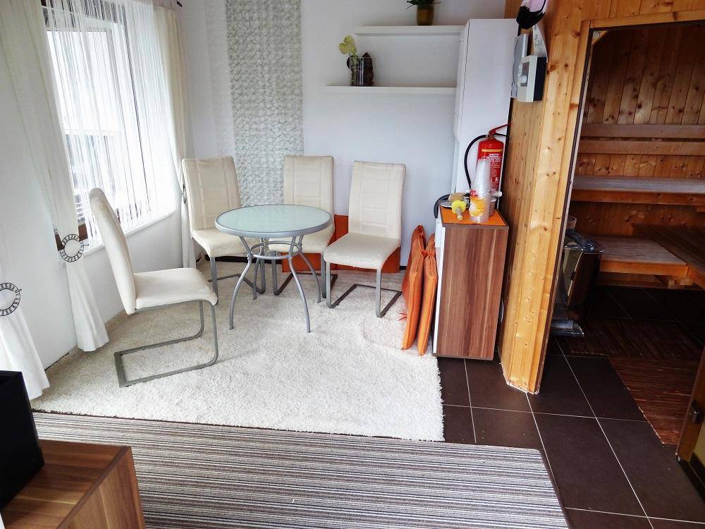 Heller Raum mit Sitzgelegenheiten, Teppichboden und direktem Zugang zu einer Sauna.