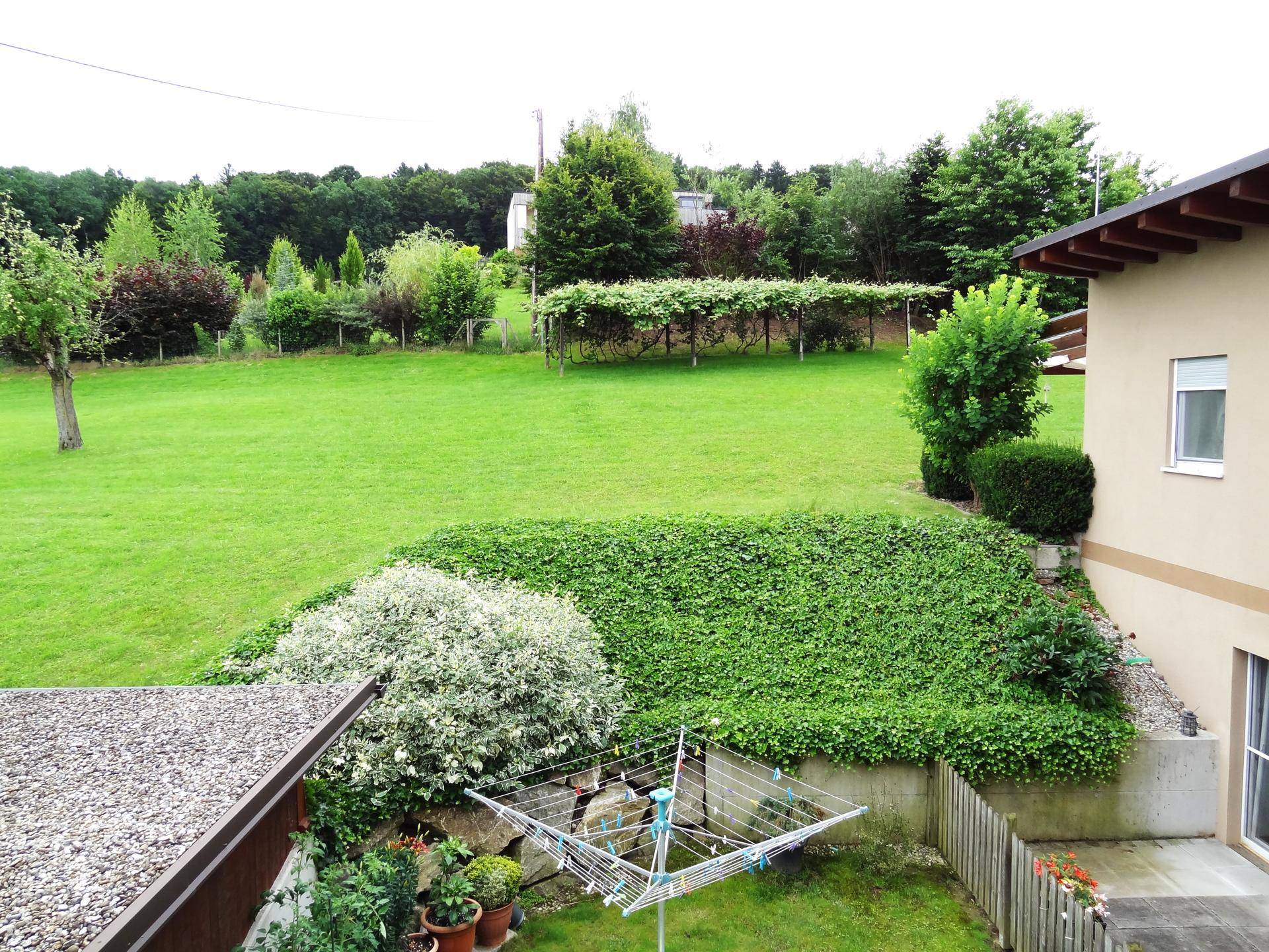 Großer, gepflegter Garten mit weitläufiger Rasenfläche und Wäscheständer im Freien.