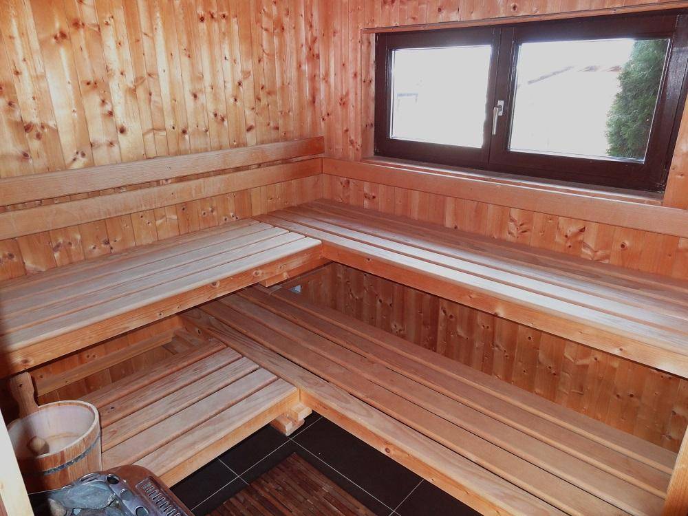 Geräumige Holzsauna mit mehreren Bänken und einem Fenster für natürliches Licht.