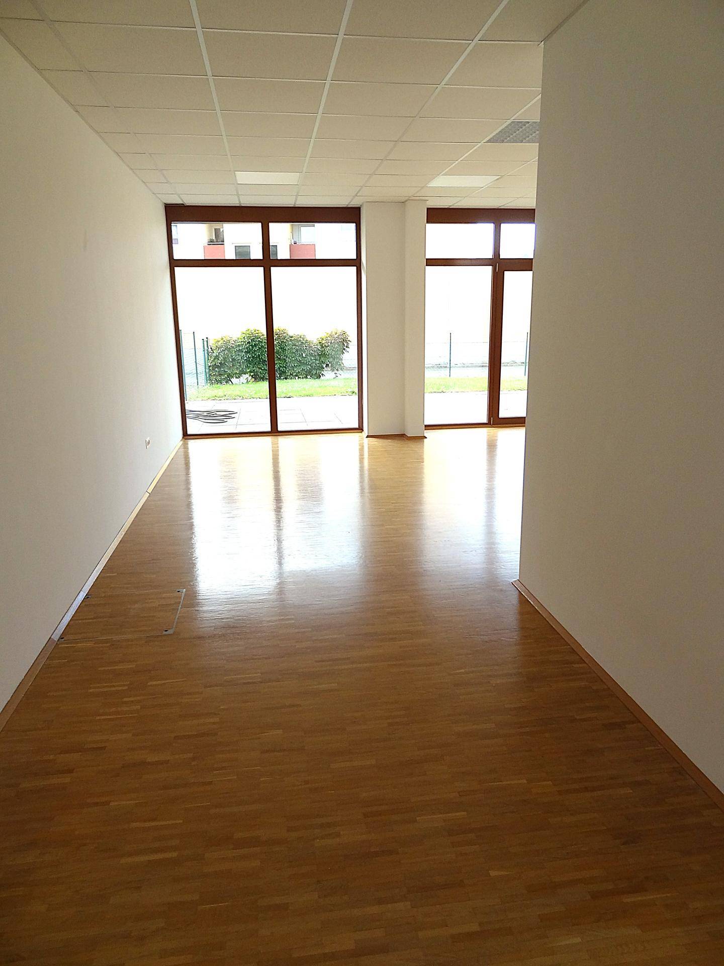 Langer, heller Flur mit Parkettboden und großen Fenstern am Ende, die den Raum erhellen.