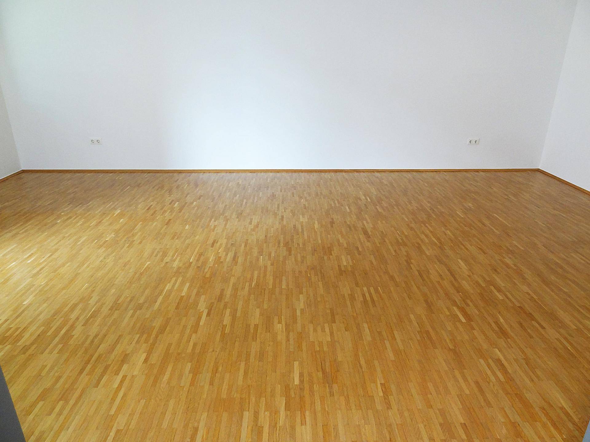 Leerer Raum mit hellem Holzboden und weißen Wänden, ideal für individuelle Gestaltung.