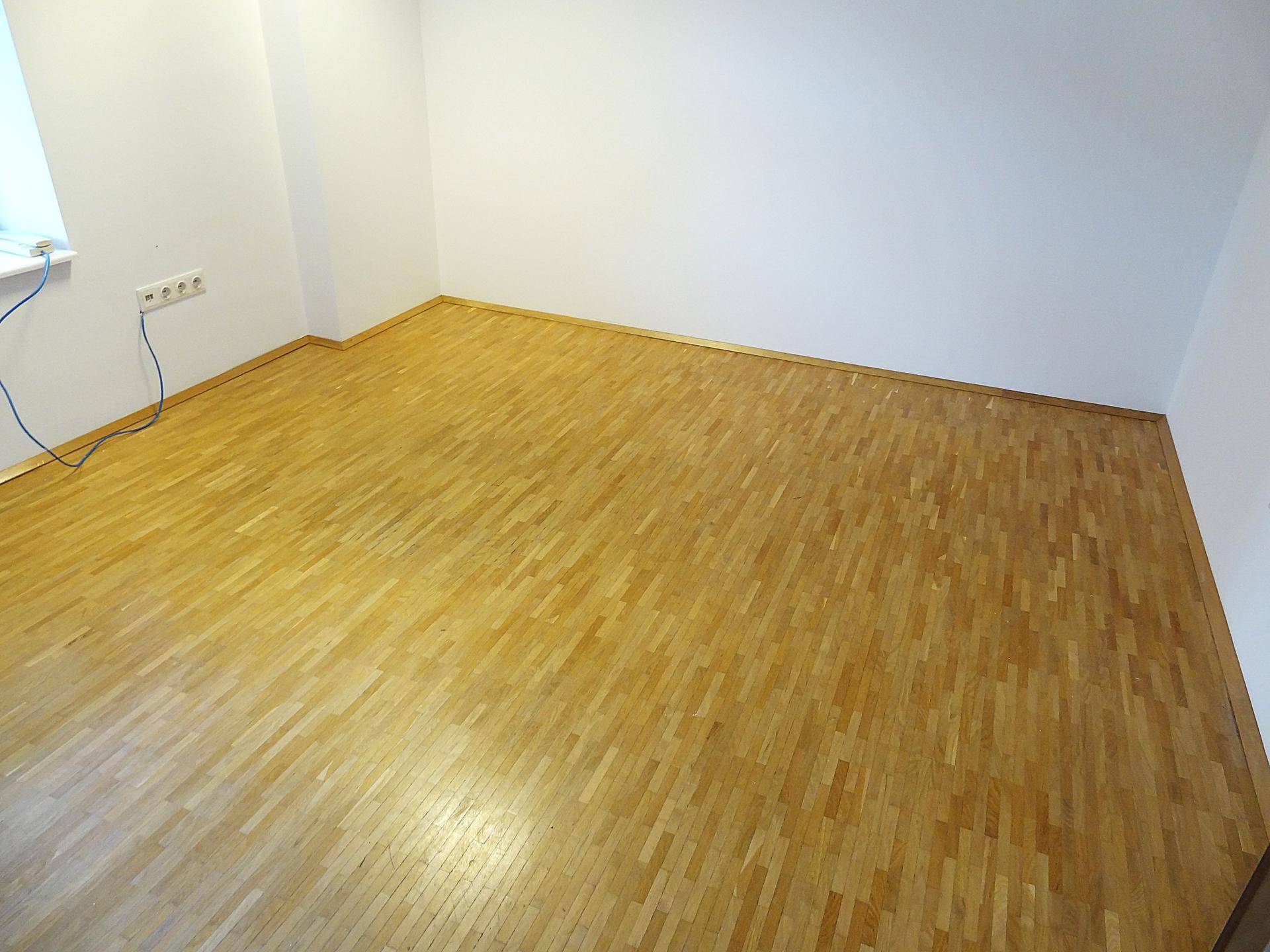 Leerer Büroraum mit Holzboden und weißen Wänden, bereit zur Nutzung.