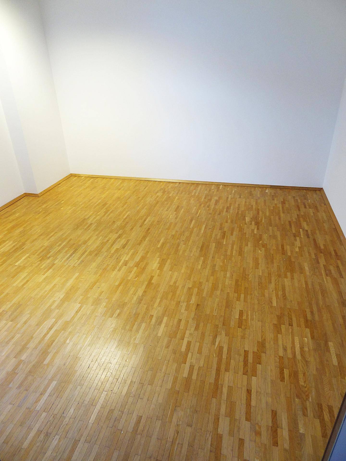 Leerer Büroraum mit Holzboden und weißen Wänden, ideal für individuelle Gestaltung.