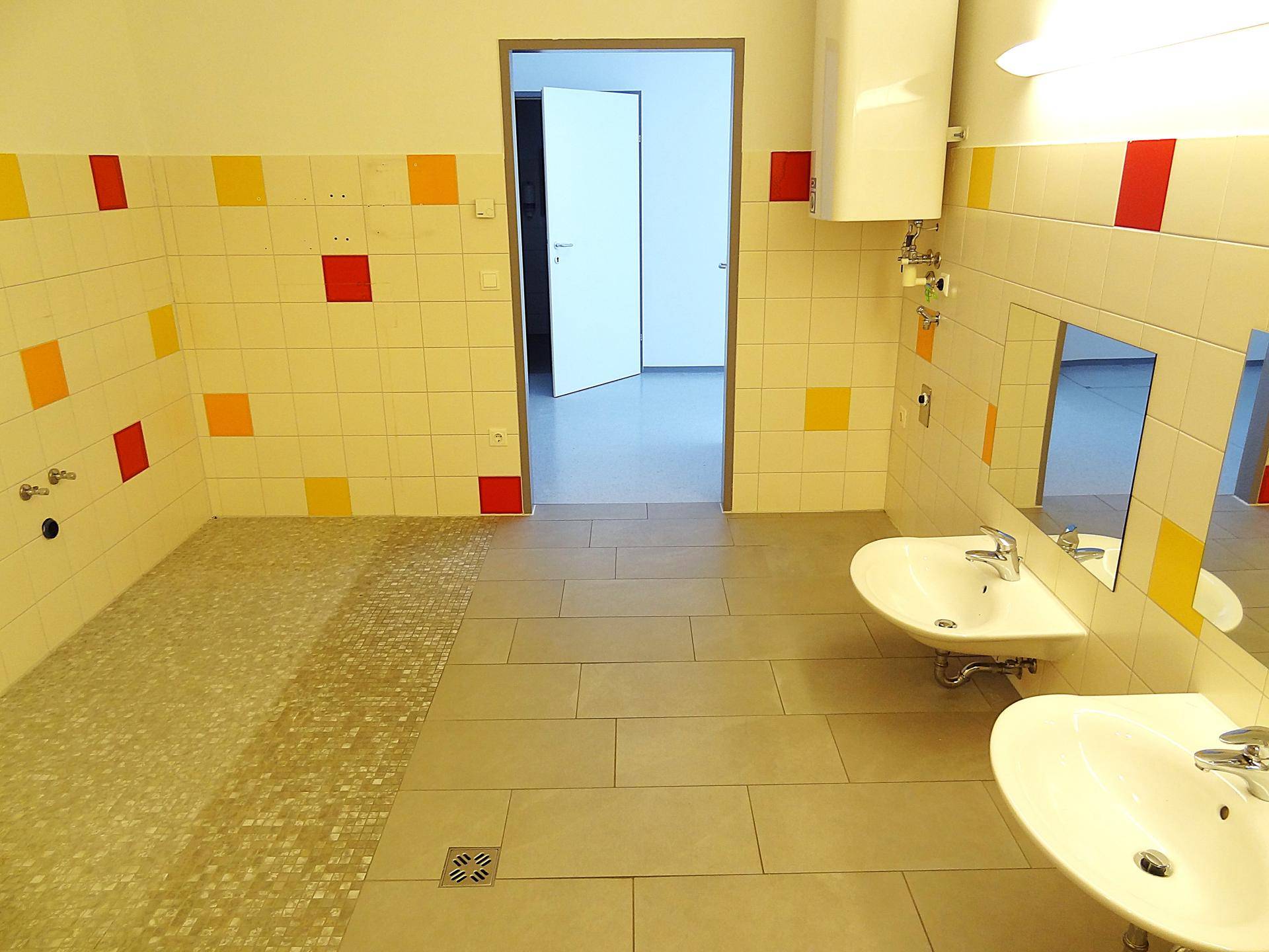Buntes Kinderbadezimmer mit Waschbecken und farbigen Fliesen, offener Zugang.