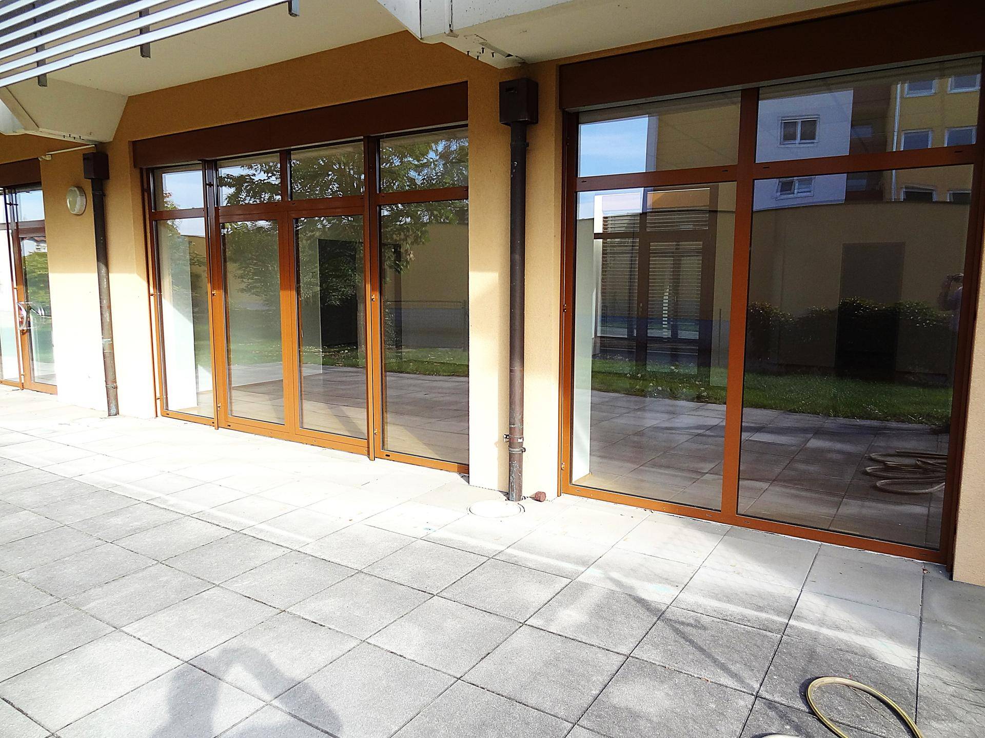 Große gepflasterte Terrasse mit breiten Fenstern und Türen, die zum Gebäude führen.