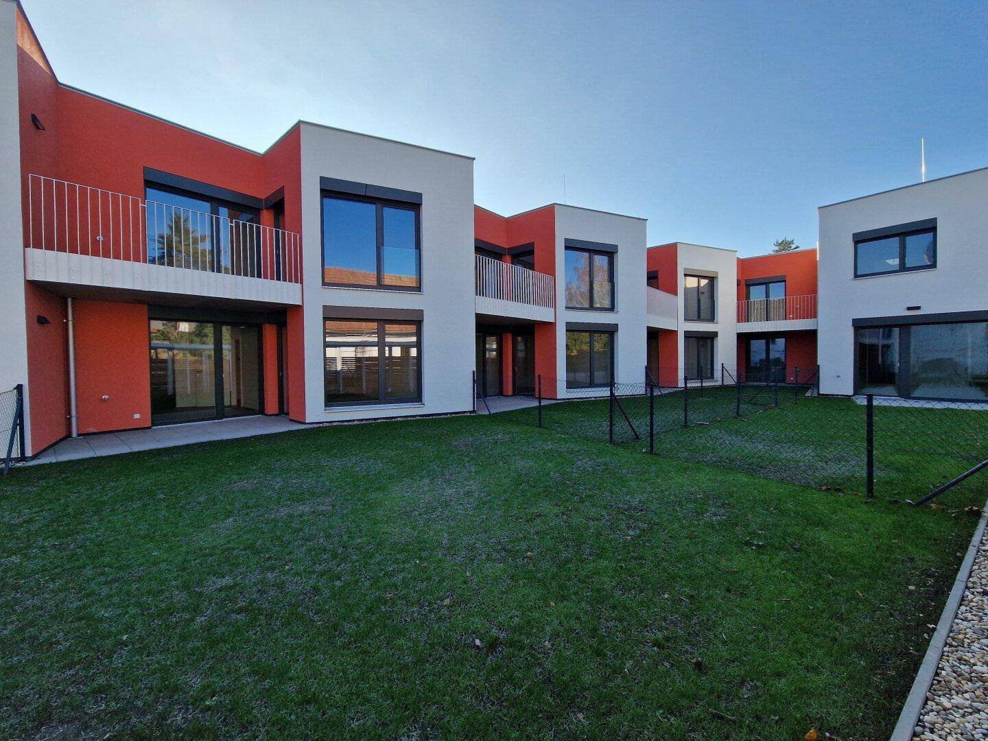 Ansicht der neuen Wohngebäude mit Balkonen und privaten Grünflächen im Vordergrund.