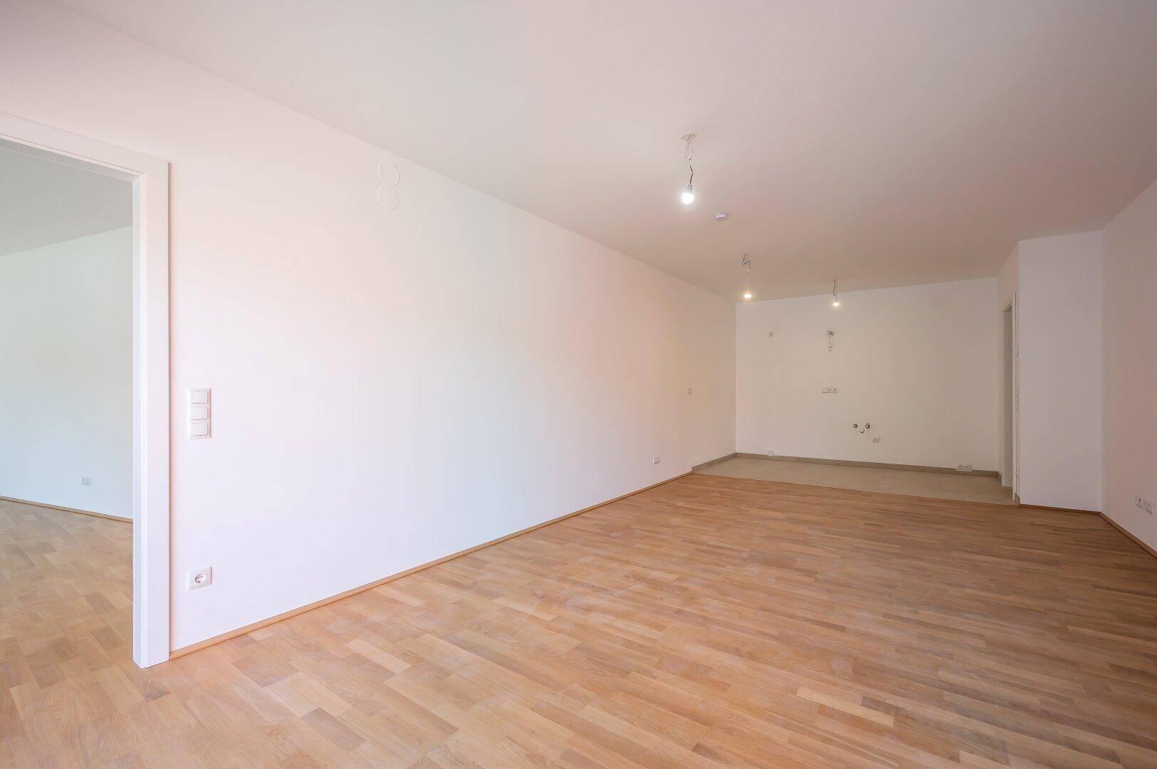 Unmöblierter Raum mit Parkettboden und weiß gestrichenen Wänden, bereit für die individuelle Gestaltung.