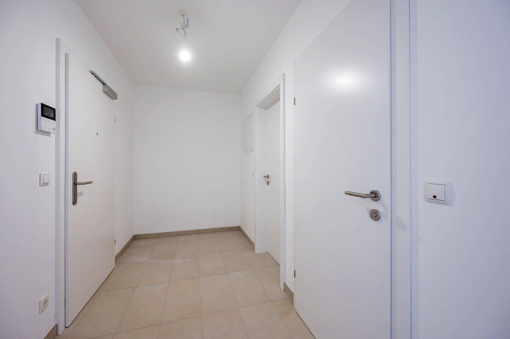 Heller Eingangsbereich mit Fliesenboden und mehreren Türen, die zu den Zimmern führen.