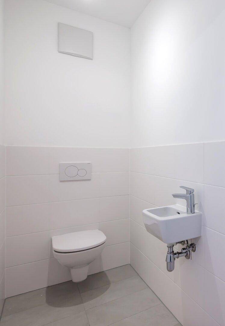 Modernes Gäste-WC mit wandhängender Toilette und kleinem Waschbecken.