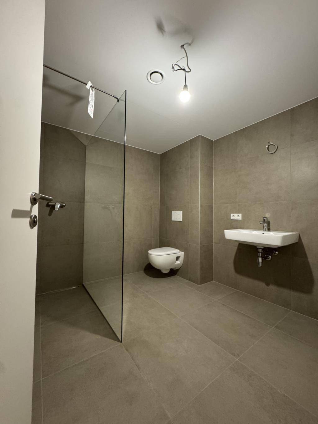 Modernes Badezimmer mit ebenerdiger Dusche, Wand-WC und Einzelwaschbecken.