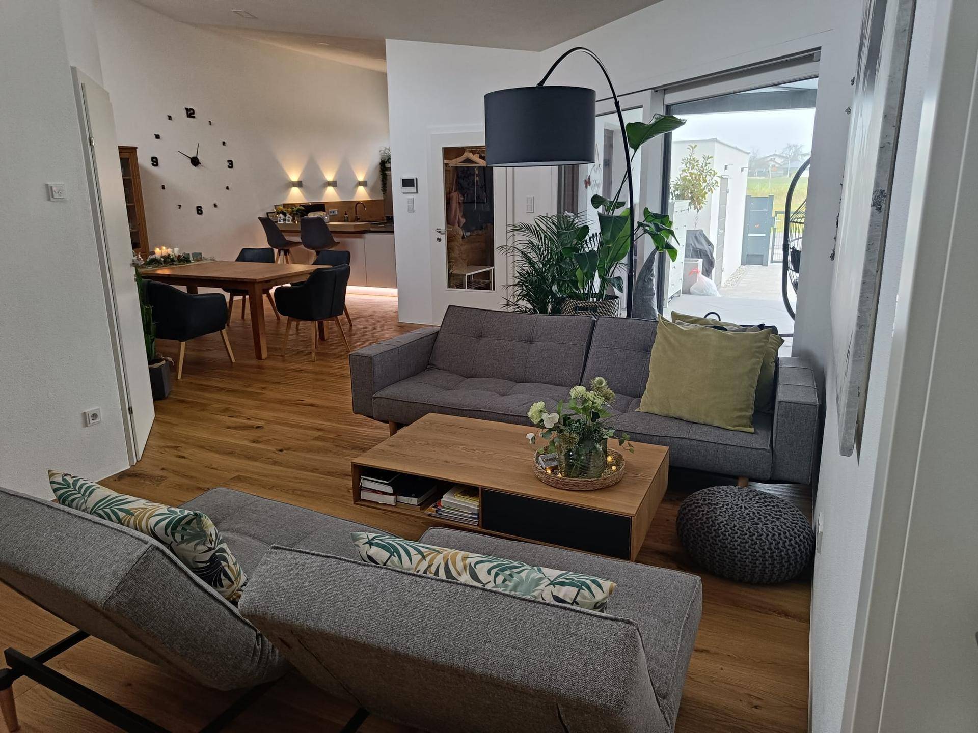 Gemütlicher Wohnbereich mit Sofa, Holzboden und offenem Übergang zum Ess- und Küchenbereich.