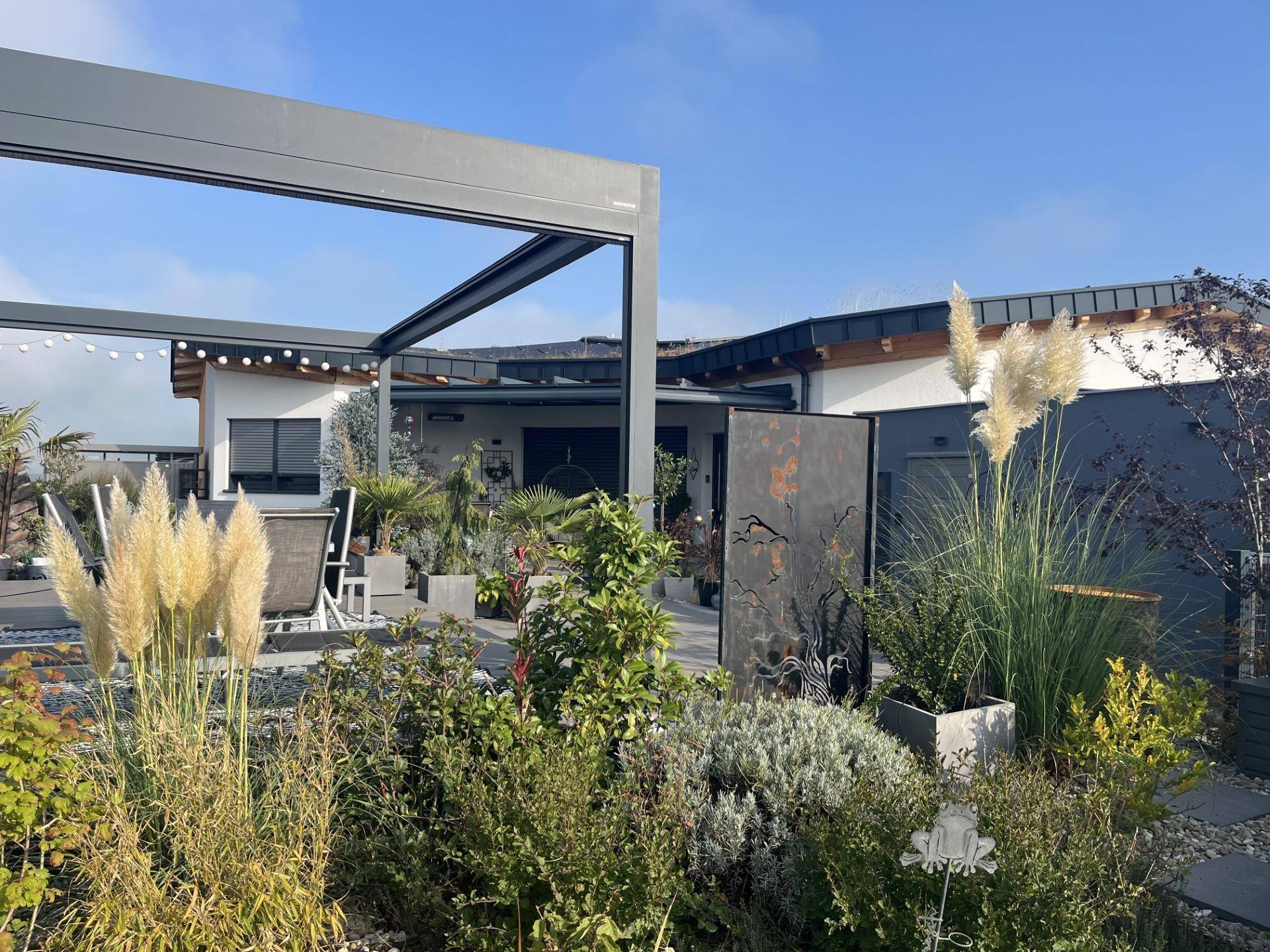 Moderner Gartenbereich mit Pergola, vielfältiger Bepflanzung und gemütlicher Sitzecke im Freien.