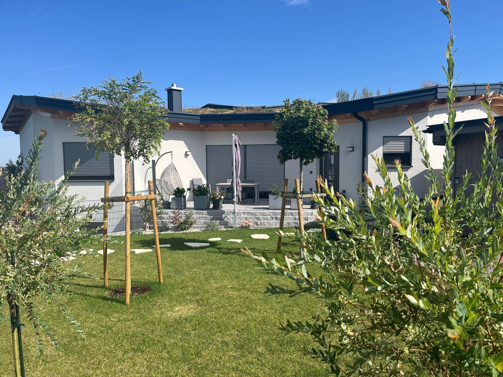 Rückseite des Hauses mit Gründach, möblierter Terrasse und frisch angelegtem Garten.