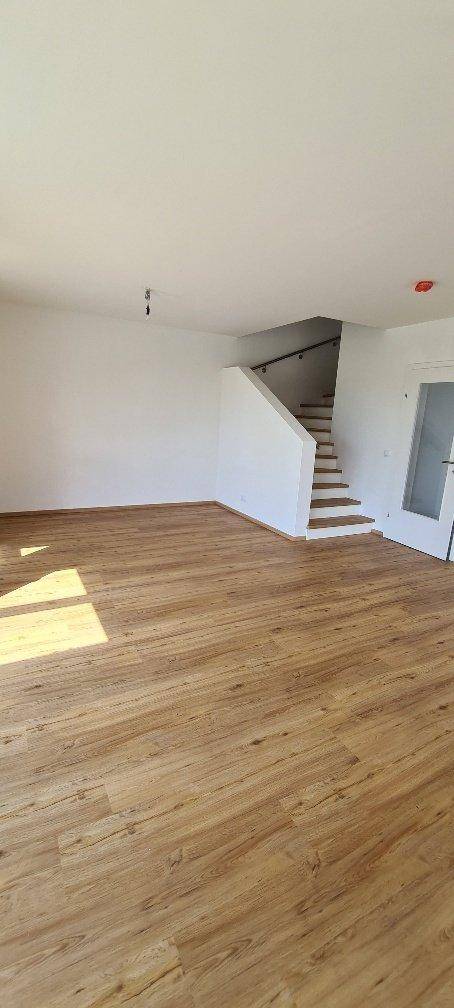 Geräumiger Wohnbereich mit Holzboden und einer Treppe, die in die obere Etage führt.