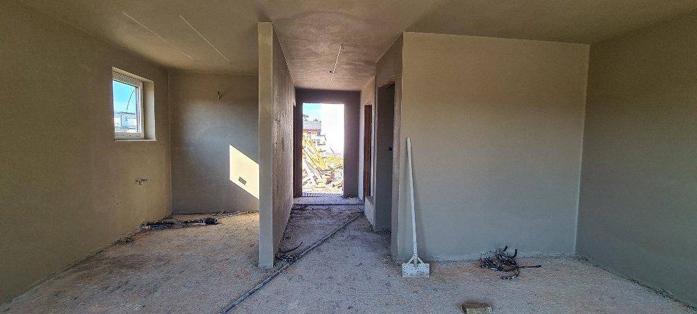 Rohbau-Innenraum mit unverputzten Wänden und einem Fenster, das natürliches Licht spendet.