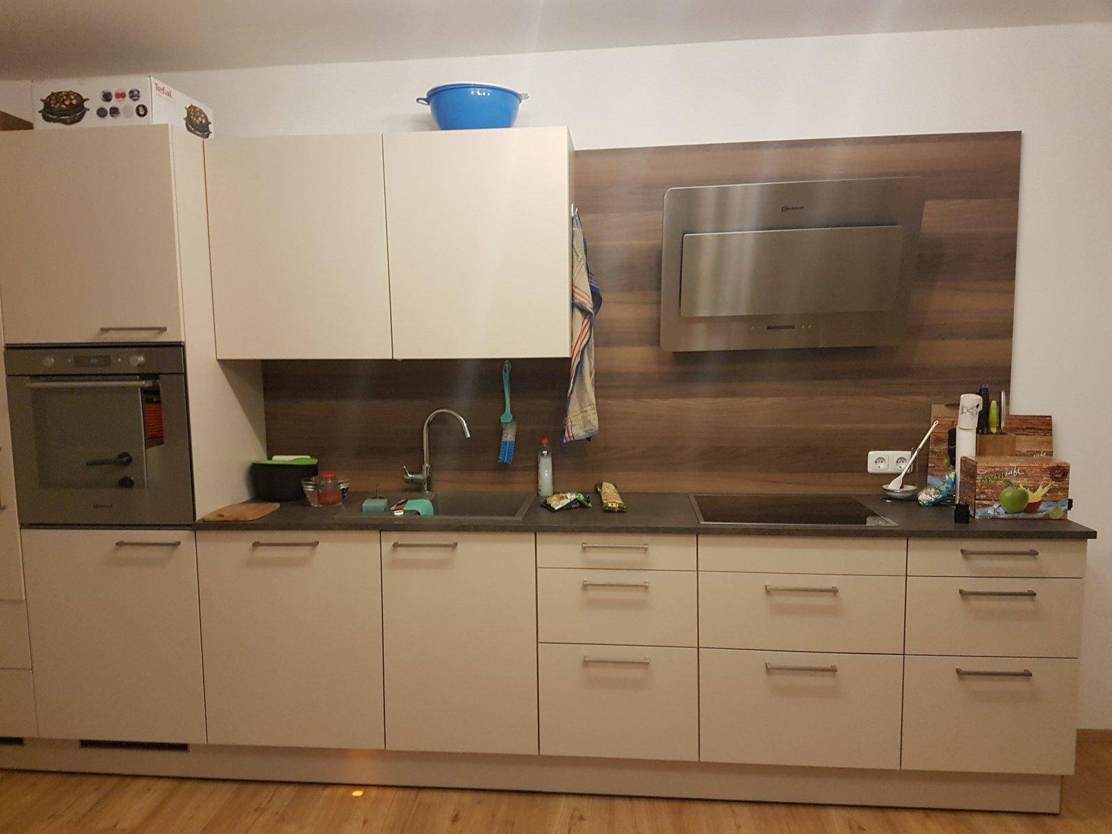Moderne Küche mit beigen Schränken, integriertem Backofen und Dunstabzugshaube.
