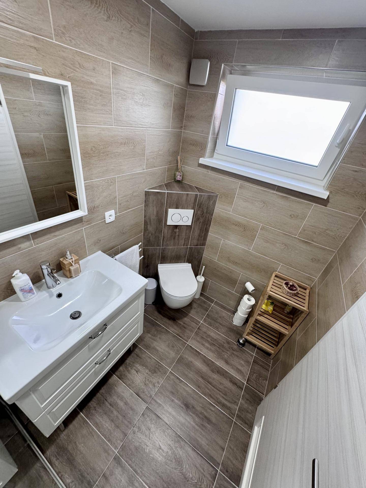 Modernes Gäste-WC mit Holzoptik-Fliesen, wandhängendem WC und Dachfenster.
