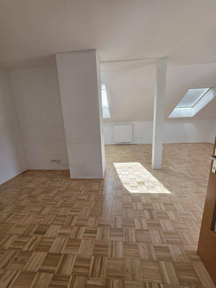 Großzügiger Wohnbereich mit Parkettboden, Dachschrägen und viel Tageslicht durch Dachfenster.
