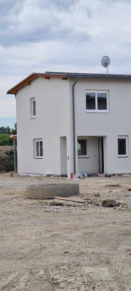 Seitenansicht des Neubaus mit einfacher Architektur und Baustellenumgebung.