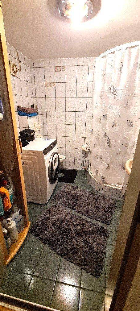 Badezimmer mit Duschkabine, WC, Waschbecken und Waschmaschine, praktisch eingerichtet.